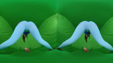 Brunette yoga girl in green fabric does intimate stretches on studio f