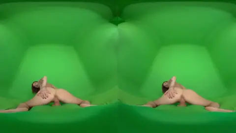 Curvy brunette with tattoos strips on green screen studio floor