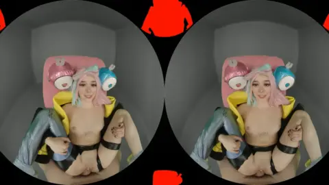 Slim white girl with colorful tattoos plays with toys topless in gray